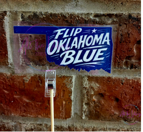 Flip Oklahoma Blue UV vinyl sticker displayed outdoors against a brick wall. Waterproof Oklahoma political decal for laptops, water bottles, tumblers, notebooks, and vehicles.