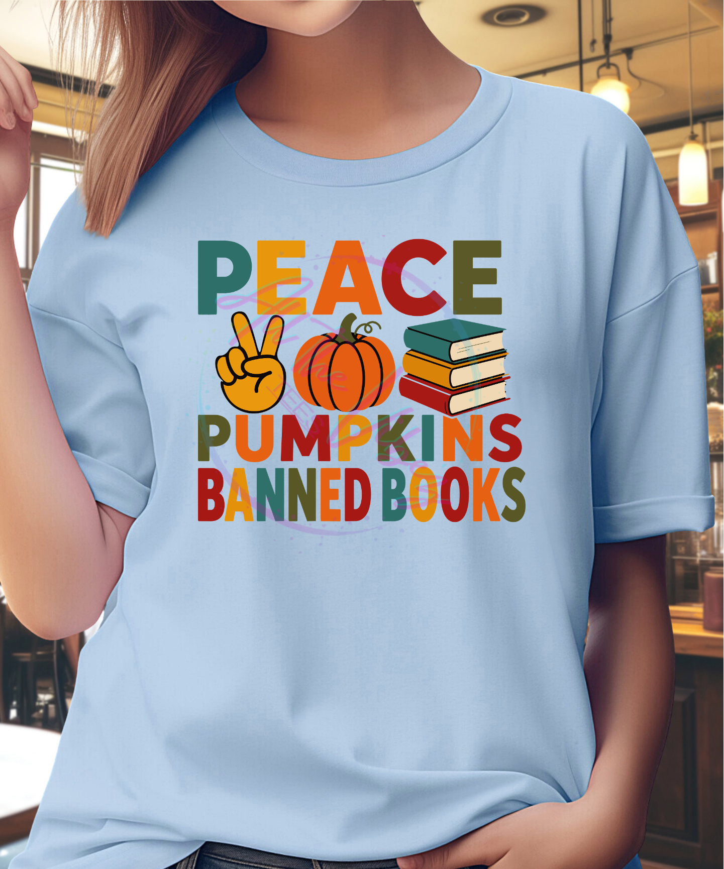 Woman wearing Peace, Pumpkins & Banned Books fall graphic tee with colorful autumn lettering celebrating cozy season and the freedom to read.