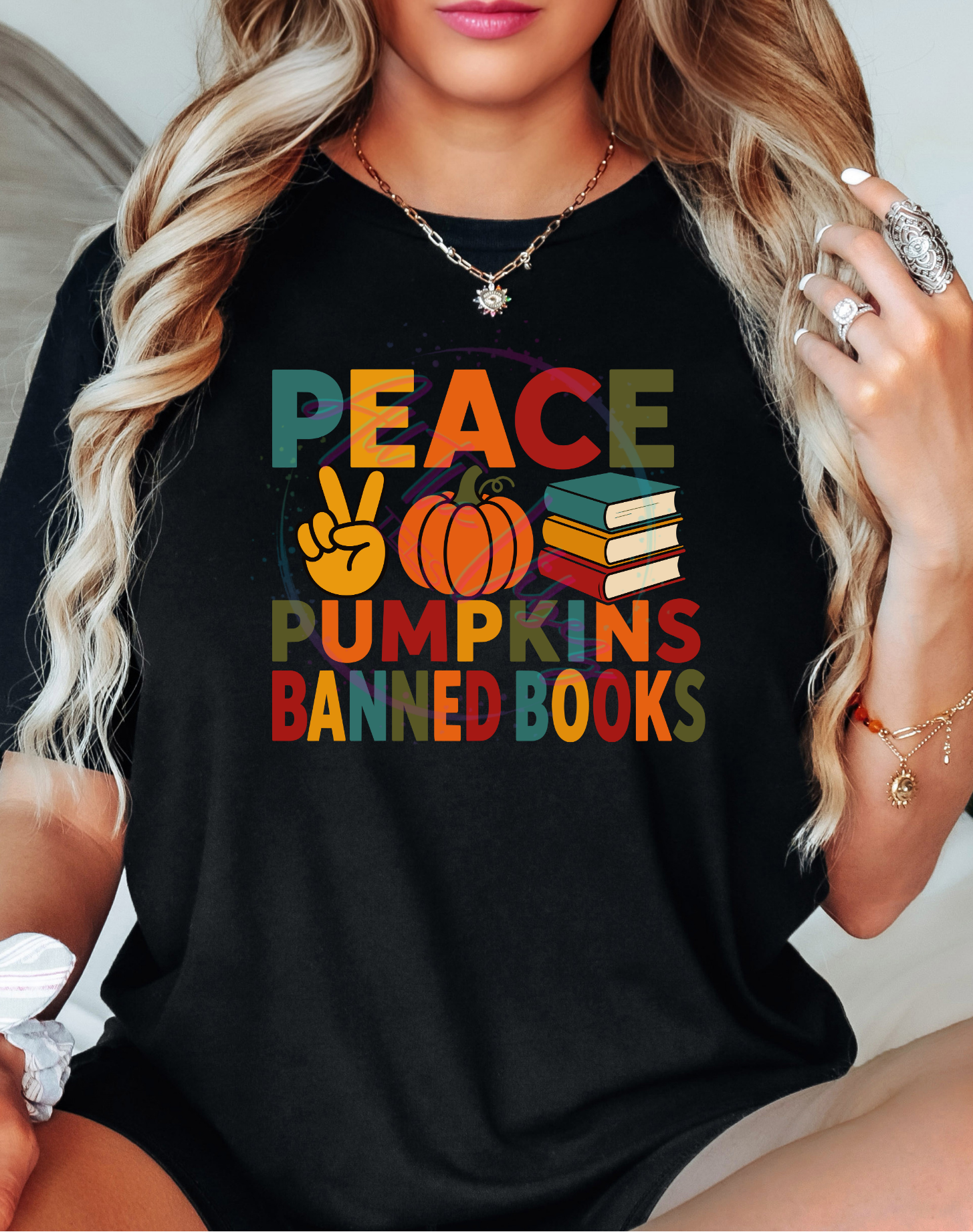 Woman wearing Peace, Pumpkins & Banned Books fall graphic tee with colorful autumn lettering celebrating cozy season and the freedom to read.